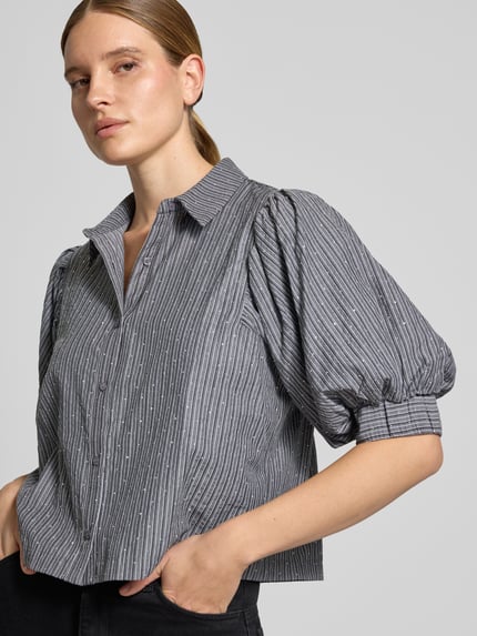 Frauenmodel trägt Bluse mit Puffärmeln Modell 'Etta' von Neo Noir, gestreiftes Design, Boxy Fit, Nahaufnahme Oberkörper.