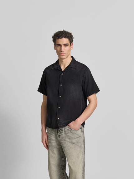 Männermodel trägt Regular Fit Jeanshemd aus Baumwolle von Diesel in Schwarz, Kurzärmelig, mit Durchgehender Druckknopfleiste und Reverskragen, Ganzkörperansicht von vorne.