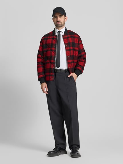 Männermodel trägt Daunenjacke mit Druckknopfleiste von Polo Ralph Lauren, rot-schwarzes Karo, Stehkragen, Baumwoll-Mix, Ganzkörperansicht von vorne.
