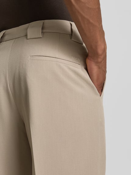 Männermodel trägt Stoffhose mit Bügelfalten und Eingrifftaschen von MCNEAL, Beige, Material-Mix mit Viskose-Anteil, Detailaufnahme Rückansicht.
