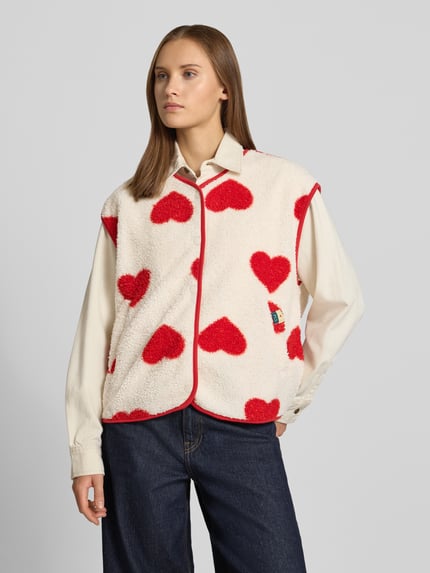 Frauenmodel trägt Regular Fit Weste mit Allover-Muster Modell 'KATTY' von PIECES, cremefarben mit roten Herzformen, Ganzkörperansicht von vorne.