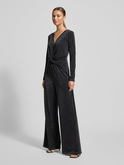 Frauenmodel trägt schimmernden Jumpsuit mit Knotendetail von Milano Italy in Dunkelgrau, weiter Schnitt, V-Ausschnitt, Ganzkörperansicht von vorne.