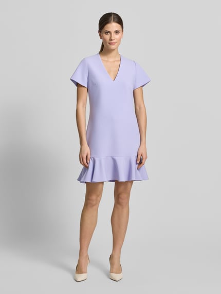 Vrouwenmodel draagt Tailliertes Etuikleid met Viskose Anteil Modell 'KABILA' van HUGO, lila uni, mini lengte, volantzoom, V-hals, korte mouw, label stitching, naadrits, strakke fit. Volledige lichaamsaanzicht van voren.
