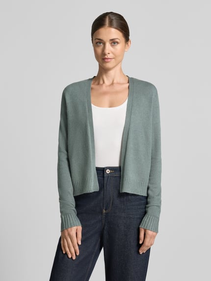 Frauenmodel trägt Strickjacke aus Viskose-Mix von VILA in Hellgrün mit geripptem Bund und gerippten Ärmelabschlüssen, gerade Passform, Ganzkörperansicht von vorne.