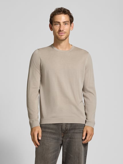 Männermodel trägt Strickpullover aus Schurwolle mit Rundhalsausschnitt von MAERZ Muenchen in Beige, glatte Textur, Ganzkörperansicht von vorne. Regular Fit, sichtbares Label-Detail, reine Schurwolle, Rückenlänge 70 cm, Ärmellänge 71 cm.
