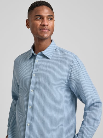 Männermodel trägt Regular Fit Freizeithemd aus Leinen-Baumwoll-Mix Modell 'CLAY LINENBLEND' von SELECTED HOMME mit Kentkragen, Melange-Optik, durchgehender Knopfleiste, langarm, 2-Knopf-Manschette, Flammgarn-Material, fein gestreiftes Muster, Blautöne, Nahaufnahme Oberkörper.