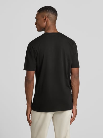 Männermodel trägt T-Shirt mit Label-Schriftzug Modell 'DULIVIO' von HUGO, Reine Baumwolle, Gerade Passform, Unifarbenes-Design, Ganzkörperansicht Rückansicht.