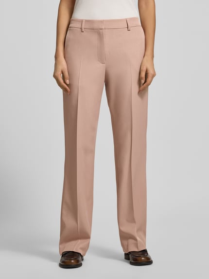 Frauenmodel trägt Stoffhose mit Gesäßtasche von Jake*s Collection in Rosa, lockerer Schnitt, Bundfalten, weich fallender Stoff, Ganzkörperansicht von vorne.