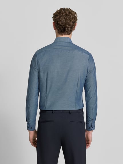 Männermodel trägt Slim Fit Businesshemd mit Kentkragen von OLYMP in Unifarbe mit feinem Webstruktur, Ganzkörperansicht Rückansicht.