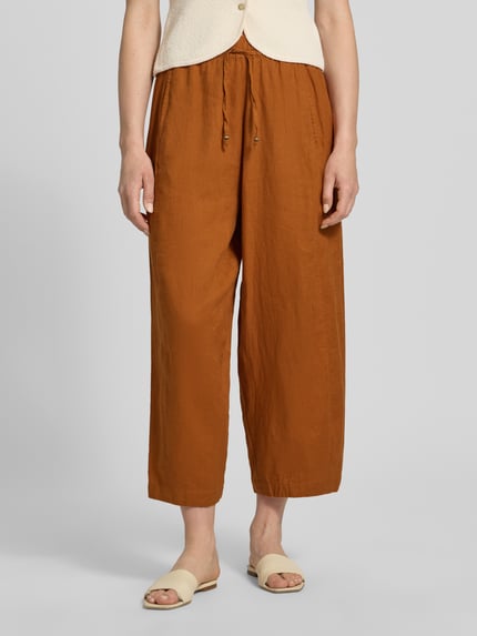 Vrouwenmodel draagt Leinenhose in verkürzter Passform mit elastischem Bund van Christian Berg Woman in zuiver linnen, wide leg, verkort, elastische band, tunnelkoord. Binnenbeenlengte maat 36: 64 cm, bandwijdte: 38 cm. Nahaufnahme onderlichaam.