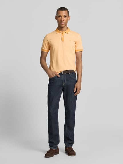 Männermodel trägt Regular Fit Poloshirt mit Logo-Stitching von Lerros in Pfirsich, Polokragen, Knopfleiste, Ganzkörperansicht von vorne.