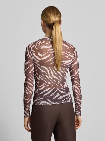 Frauenmodel trägt Slim Fit Longsleeve in semitransparentem Design von COMMA mit braun-weißem Muster, Ganzkörperansicht Rückansicht.