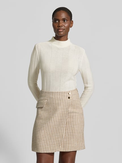 Frauenmodel trägt Strickpullover aus Schurwolle-Mix mit Stehkragen von Marc Cain, Slim Fit, cremefarben, Nahaufnahme Oberkörper.