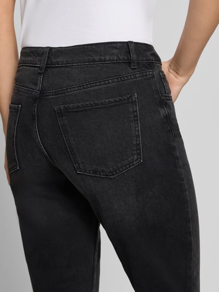 Frauenmodel trägt Straight Fit Jeans aus Baumwoll-Mix von REVIEW, dunkle Waschung, 5-Pocket-Design, Nahaufnahme Rückansicht.