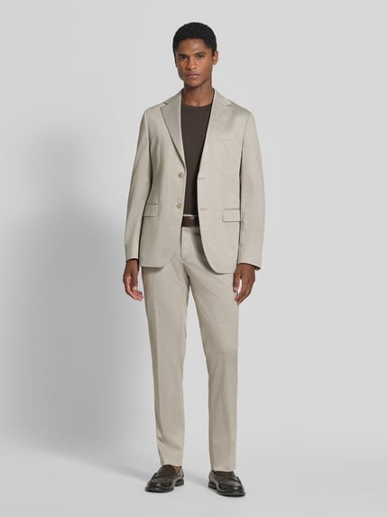 Männermodel trägt Straight Fit Stoffhose mit Viskose-Anteil von HECHTER PARIS in Beige, klassische Eingriff- und Gesäßtaschen, Ganzkörperansicht von vorne. Elastischer Material-Mix, Knopf- und Reißverschluss, Bundweite 44 cm, Innenbeinlänge 47 cm.