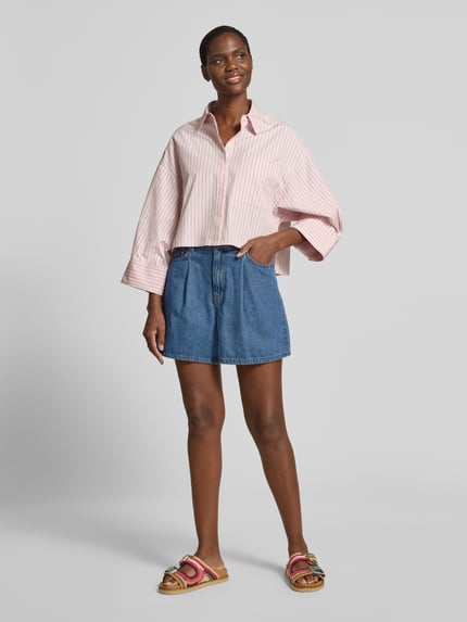 Frauenmodel trägt Jeansshorts mit Eingrifftaschen Modell 'GEMMA' von YAS in Blau, Reine Baumwolle, Regular-Fit, Ganzkörperansicht von vorne, Bundweite bei Größe 36: 37 cm, Innenbeinlänge bei Größe 36: 41 cm.