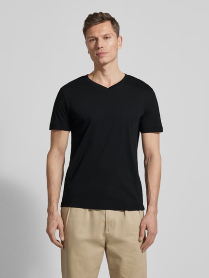 Männermodel trägt Regular Fit T-Shirt aus reiner Baumwolle von Tom Tailor, unifarben, V-Ausschnitt, kurzarm, Logo-Stitching, Ganzkörperansicht von vorne.