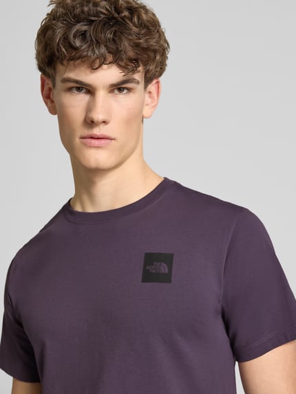 Męski model nosi T-Shirt aus Baumwoll-Mix Modell 'EVOLUTION' von The North Face, krój regular fit, fioletowy, z nadrukiem logo, zbliżenie na górną część ciała.
