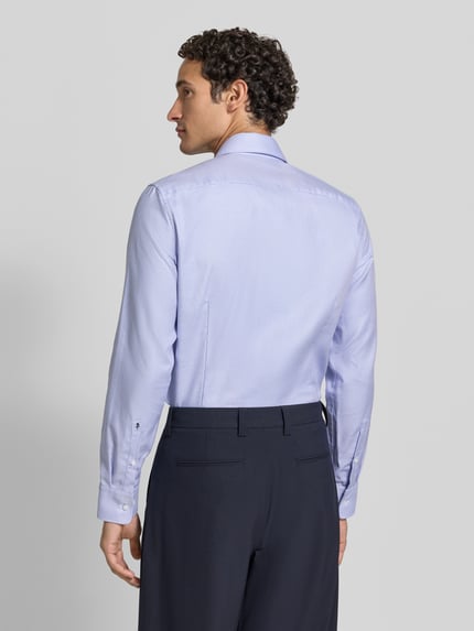 Męski model nosi jasno niebieską koszulę Slim Fit Businesshemd aus reiner Baumwolle von Seidensticker, widok całej sylwetki z tyłu.