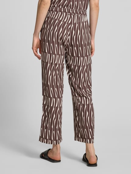 Frauenmodel trägt Wide Leg Stoffhose aus Viskose Modell 'Marou bamboo' von OPUS mit braun-beigem Allover-Muster, Ganzkörperansicht Rückansicht.