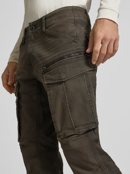 Männermodel trägt Regular Tapered Cargohose aus Baumwoll-Mix Modell 'Rovic' von G-Star RAW, Olivgrün, Popeline-Textur, Nahaufnahme Oberschenkel, seitliche Ansicht.