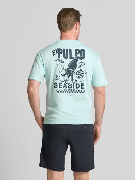 Männermodel trägt Regular Fit T-Shirt aus reiner Baumwolle von s.Oliver RED LABEL in lichtblauw met grote print op de rug, ganzkörperansicht rückansicht.