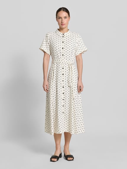Vrouwenmodel draagt overhemdjurk met stippen, strikceintuur, overhemdkraag, knoopsluiting, mouwen met omslag, model 'BlakeLL' van LOLLYS LAUNDRY, getailleerd model, midi-jurk, ruglengte maat S 122 cm, borstwijdte 50 cm, mouwlengte 21 cm, geheel lichaamsaanzicht van voren.