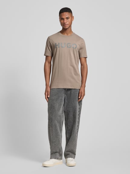 Męski model nosi Relaxed Fit T-Shirt aus reiner Baumwolle Modell 'DULIVIO' von HUGO, jednokolorowy, okrągły dekolt, dżersej, z napisem z logo, krótki rękaw, cała sylwetka z przodu.