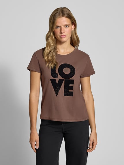 Frauenmodel trägt Regular Fit T-Shirt aus reiner Baumwolle Modell 'BEATRISA' von Pepe Jeans in Braun mit schwarzem Print, Ganzkörperansicht von vorne, Damen T-Shirt von Pepe Jeans.