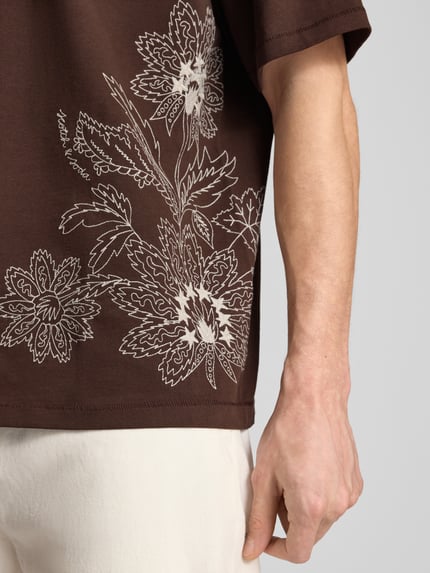 Männermodel trägt Loose Fit T-shirt met Stitchings van Scotch & Soda, puur katoen, ronde hals, ruglengte bij maat M 71 cm, detailopname rechterzij
