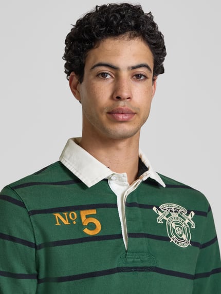 Männermodel trägt Regular Fit Rugby Shirt mit Logo- und Motiv-Stitching von Superdry, Reine Baumwolle, Polokragen, Nahaufnahme Oberkörper.