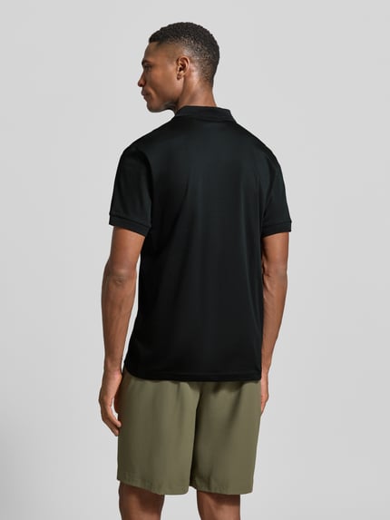 Männermodel trägt Regular Fit Poloshirt aus reiner Baumwolle Modell 'PS Spirit 70 Plk' von BOSS Green X PORSCHE, unifarben, Ganzkörperansicht Rückansicht.