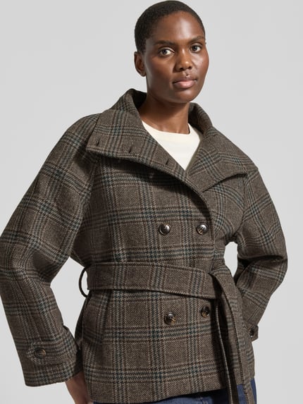 Frauenmodel trägt Jacke mit Stehkragen und Bindegürtel Modell 'Munet' von Neo Noir im Karo-Muster, Material-Mix, Nahaufnahme Oberkörper.