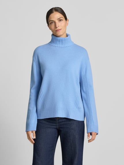 Frauenmodel trägt Relaxed Fit Rollkragenpullover aus reiner Wolle von Liu Jo White in Hellblau mit Strasssteinen, gerippten Abschlüssen, Ganzkörperansicht von vorne.