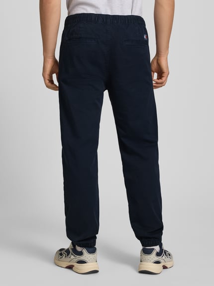 Männermodel trägt Straight Fit Jeans aus reiner Baumwolle von Tommy Jeans in Dunkelblau, elastischer Bund, 5-Pocket, Ganzkörperansicht Rückansicht.