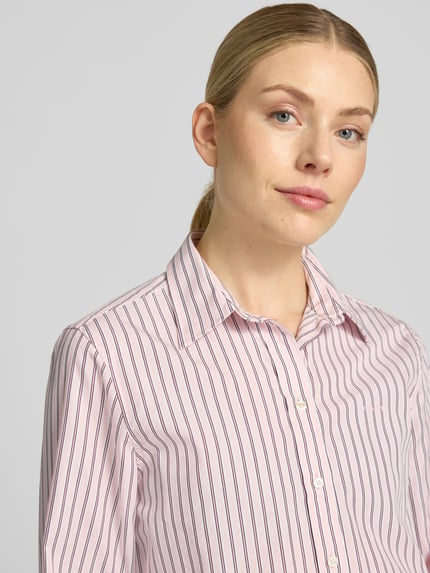 Vrouwenmodel draagt Regular fit blouse met lange mouwen van puur katoen van GANT, wit met roze en blauwe strepen, Nahaufnahme Oberkörper.