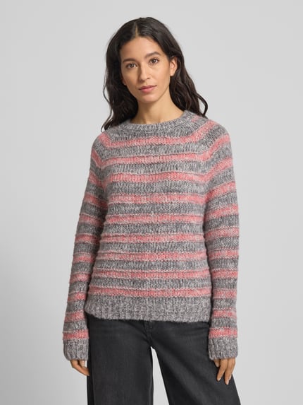Kobieta modelka nosi Strickpullover mit Strukturmuster und Rundhalsausschnitt od Smith and Soul, mix materiałów z alpaką, regular fit, szare i różowe paski, widok całej sylwetki z przodu.