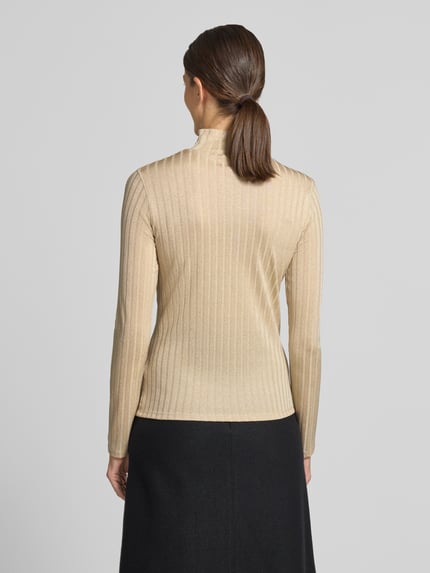 Frauenmodel trägt Longsleeve mit Rollkragen von Marc Cain in hellem Beige mit Ripp-Struktur, Glitzer-Garn, geradem Schnitt, Rückenansicht. Viskose-Mix mit Stretch-Anteil, Rückenlänge 58 cm, Label-Applikation.