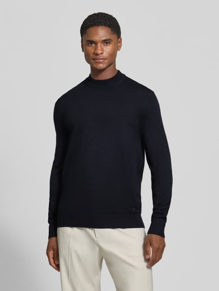 Männermodel trägt Regular Fit Pullover aus reiner Schurwolle Modell 'Davide' von JOOP! COLLECTION in Dunkelblau, Ganzkörperansicht von vorne.