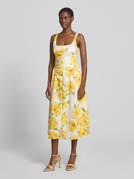 Frauenmodel trägt Midikleid im Allover-Look Modell 'ISLAND' von MANGO, gelbe Blumen auf weiß, Baumwoll-Elasthan-Mix, A-Linie, Karree-Ausschnitt, Ganzkörperansicht von vorne.