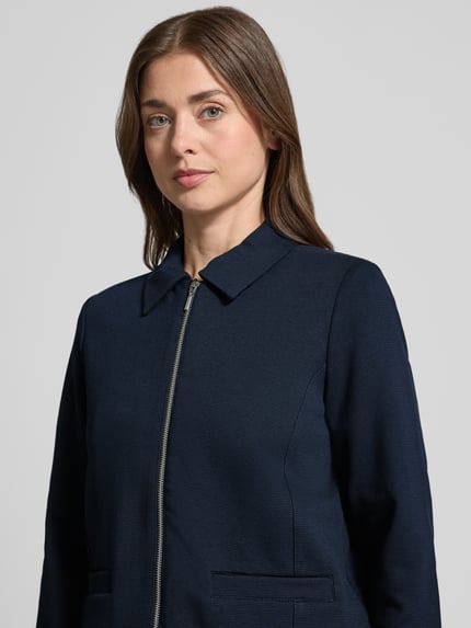 Vrouwenmodel draagt Regular Fit Kurzblazer aus Baumwoll-Mix van Tom Tailor, look: effen, platte kraag, ritssluiting, lange mouw, zij-steekzakken, materiaalverwerking: ottoman-rib, Nahaufnahme bovenlichaam.