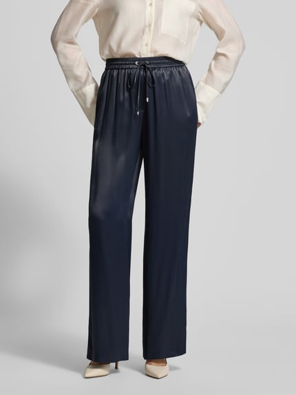Frauenmodel trägt Wide Leg Hose aus reiner Viskose Modell 'TAVATI' von BOSS in Dunkelblau, satinierte Textur, unifarben, Ganzkörperansicht von vorne.