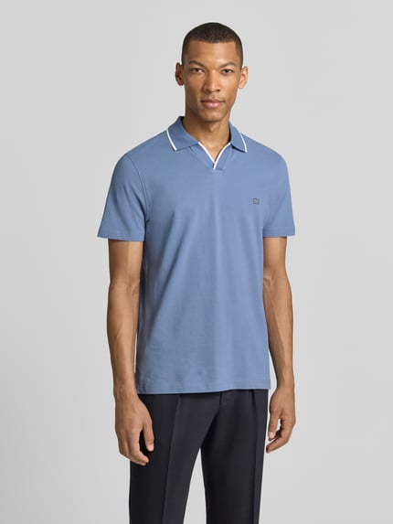 Männermodel trägt Modern Fit Poloshirt mit Logo-Stitching von Christian Berg Men in Blau, kurze Ärmel, reine Baumwolle, Ganzkörperansicht von vorne.