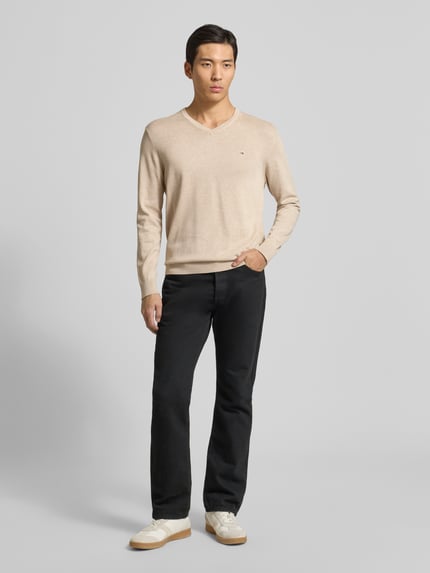 Męski model nosi Strickpullover mit V-Ausschnitt von Christian Berg Men z bawełny w kolorze beżowym, regular fit, widok całej sylwetki z przodu.