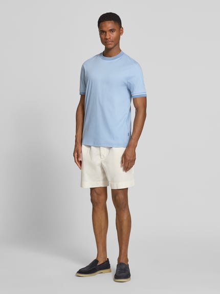 Männermodel trägt Slim Fit T-Shirt aus reiner Baumwolle Modell 'H-TESSLER 238' von BOSS in Hellblau, Kontrastnähte, unifarben, Ganzkörperansicht von vorne.