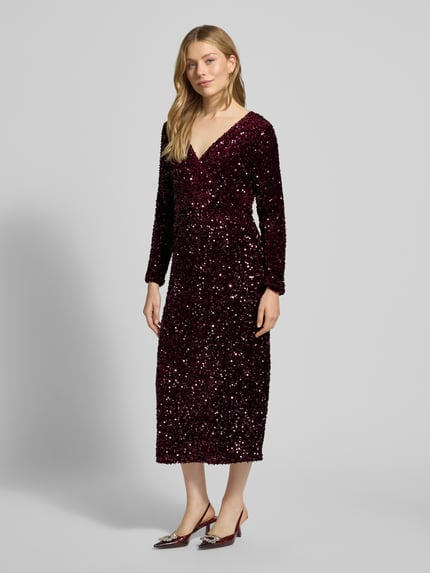 Frauenmodel trägt Midikleid mit V-Ausschnitt Modell 'FAITH' von Vila, bordeauxrot, Pailletten, tailliert, langärmlig, Ganzkörperansicht von vorne.