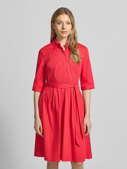 Vrouwenmodel draagt knielang 'Knielanges Hemdblusenkleid mit Bindegürtel' van Christian Berg Woman Selection in rood katoenmix met stretch, A-lijn, verborgen knoopsluiting, strikceintuur, ruglengte maat 36: 99 cm, borstwijdte maat 36: 48 cm, mouwlengte maat 36: 37 cm, geheel van voren.