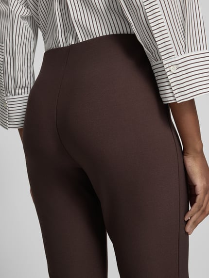 Frauenmodel trägt High Waist Stoffhose mit Bügelfalte Modell 'Elvina' von OPUS, Struktur in dunkelbrauner Webware, Nahaufnahme Rückansicht.
