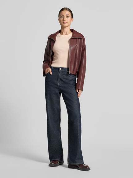 Kobiece modelka nosi Skinny Fit Tanktop aus reiner Baumwolle od DRYKORN w kolorze beżowym, efekt prążkowania, okrągły dekolt, długość tyłu w rozmiarze S to 54 cm, widok na całe ciało z przodu.