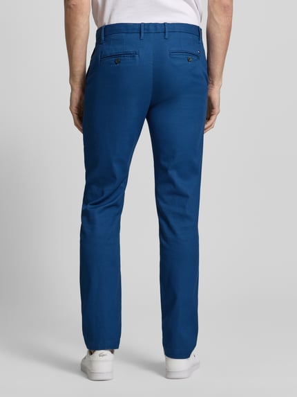 Mężczyzna nosi Slim Fit Chino aus Baumwoll-Mix od Tommy Hilfiger w jednolitym niebieskim kolorze, materiał piké, widok całej sylwetki od tyłu.